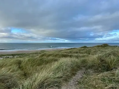 a sandy beach with the ocean in the background at Vesterhavsluft Og Natur Ved Nationalpark Thy in Thisted