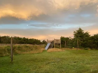 a wooden staircase in a grassy field with a sunset at Vesterhavsluft Og Natur Ved Nationalpark Thy in Thisted
