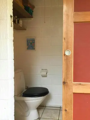 a bathroom with a toilet with a black seat at Summer House In The Dunes Near The West Sea in Saltum