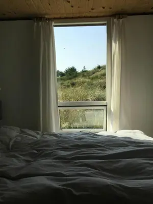a bedroom with a bed and a large window at Summer House In The Dunes Near The West Sea in Saltum