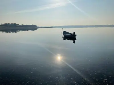 a boat is sitting on a large body of water at Stunning Sunrises Over Harre Vig in Roslev