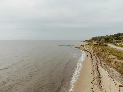 a beach next to the ocean on a cloudy day at Summer House With Panoramic Views Of The Limfjord in Lihme