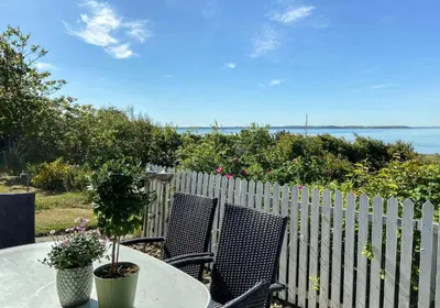 a table with two chairs and a fence at Summer House With Panoramic Views Of The Limfjord in Lihme