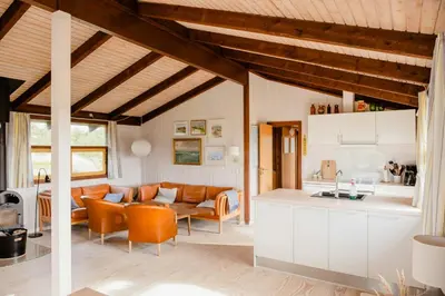an open kitchen and living room with orange chairs at Family Home In Heather-Clad Landscape in Fjerritslev