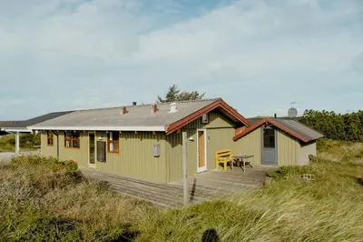 a yellow house with a table and a wooden deck at Family Home In Heather-Clad Landscape in Fjerritslev