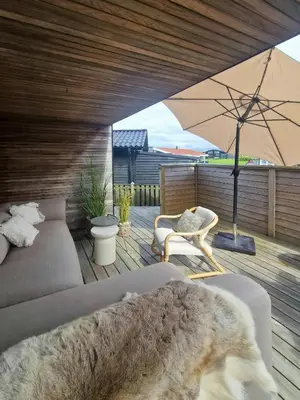 a patio with a couch and an umbrella on a deck at Panoramic Views Of Venø Bay At Handbjerg Marina