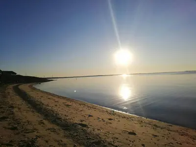 a beach with the sun rising over the water at Panoramic Views Of Venø Bay At Handbjerg Marina