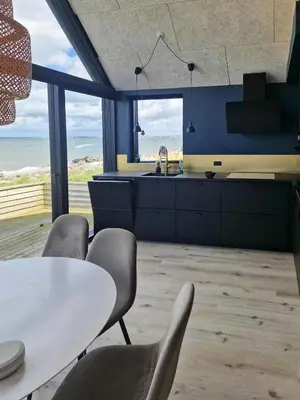 a kitchen with a table and chairs and the ocean at Panoramic Views Of Venø Bay At Handbjerg Marina