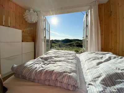 a bedroom with a bed and a large window at Luxury With Pool In Dunes Near Løkken in Løkken