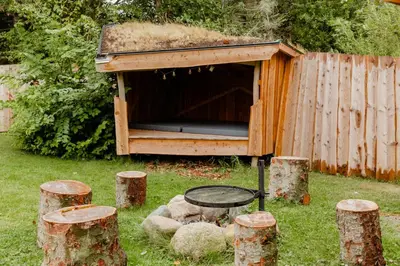 a wooden dog house with a table and some logs at Family Summer House Close To The North Sea in Vestervig