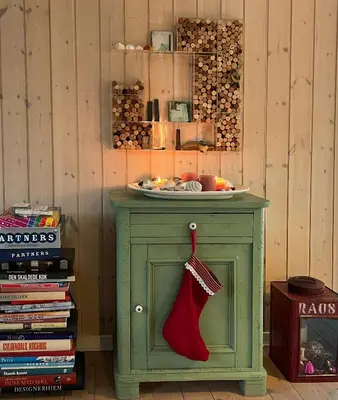 a green cabinet with a stocking on it next to a stack of books at Creative Family House Near Blokhus Beach in Blokhus