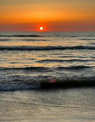an orange sunset over the ocean with waves at Creative Family House Near Blokhus Beach in Blokhus