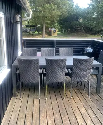a table and chairs on a deck with a grill at North Sea's Expanse Near Vorupør in Thisted