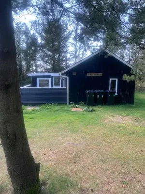 a black house with a tree in front of it at North Sea's Expanse Near Vorupør in Thisted