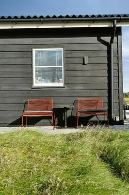 two red benches sitting in front of a building at Minimalist Coziness By The Wild North Sea in Harboør
