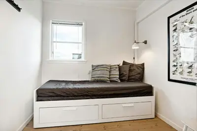 a bed in a room with a window at Minimalist Coziness By The Wild North Sea in Harboør