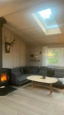 a living room with a couch and a table at Holiday Home In Tranum Forest in Brovst