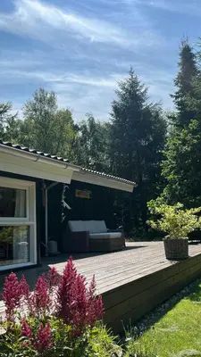 a wooden deck with a couch on a house at Holiday Home In Tranum Forest in Brovst