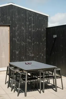 a table and chairs in front of a black wall at Architect-Designed House Close To The North Sea in Vestervig