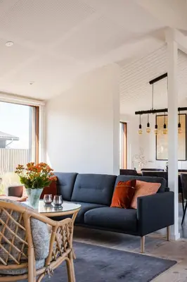a living room with a blue couch and a table at Architect-Designed House Close To The North Sea in Vestervig