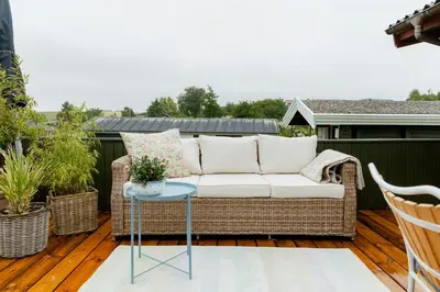 a wicker couch on a deck with a table at Grandma's House By Limfjord And Fur in Roslev