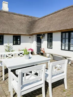 a white table and two chairs in front of a house at Historic House With Fjord View On Venø in Vemb
