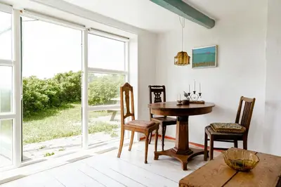 a dining room with a table and a large window at Magical Farm House Right Next To The Sea in Lemvig