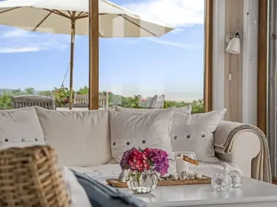 a white couch with a vase of flowers on a table at Holiday Home Bjerund - 300m from the sea by Interhome in Løkken
