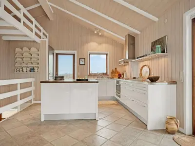 a large kitchen with white cabinets and windows at Holiday Home Bjerund - 300m from the sea by Interhome in Løkken
