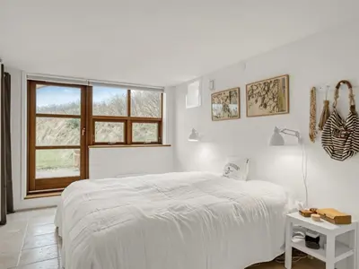 a white bedroom with a bed and a window at Holiday Home Bjerund - 300m from the sea by Interhome in Løkken