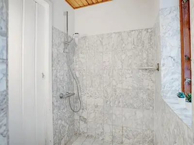 a bathroom with a shower with a stone wall at Holiday Home Star - 200m to the fjord by Interhome in Farsø