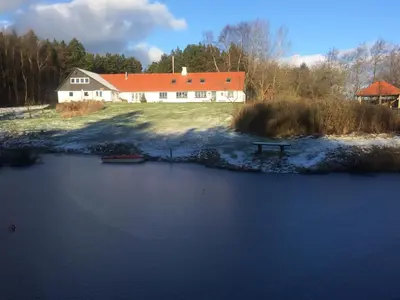 a house with an orange roof next to a lake at Alt det bedste mellem hav og fjord - en hel bolig in Brovst