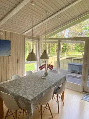 a dining room with a table and chairs and a large window at Sommerhus i Rødhus Blokhus in Pandrup