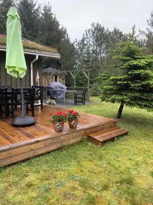 a wooden deck with two potted plants on it at Sommerhus i Rødhus Blokhus in Pandrup