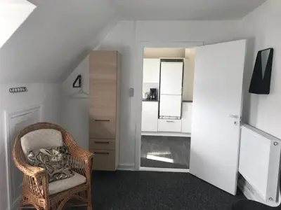 a living room with a chair and a mirror at Svanegade 1 , 2 sal in Thyborøn