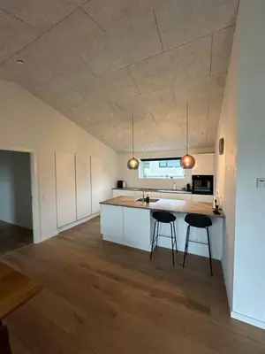 a kitchen with two bar stools and a kitchen island at Moderne nybygget in Holstebro