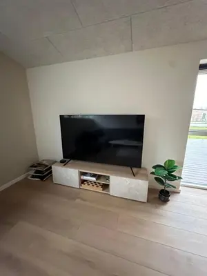 a flat screen tv on a stand in a living room at Moderne nybygget in Holstebro