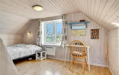 a bedroom with a bed and a chair in a room at Two-Bedroom Holiday Home Thyholm With Sea View 04 in Thyholm