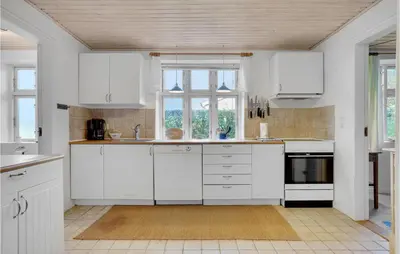 a white kitchen with white cabinets and a window at Two-Bedroom Holiday Home Thyholm With Sea View 04 in Thyholm