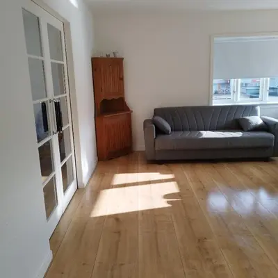 a living room with a couch and a wooden floor at Hyggelig lejlighed i stille by in Vemb