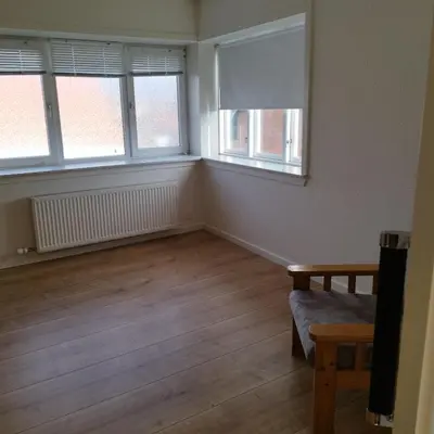 an empty living room with two windows and a couch at Hyggelig lejlighed i stille by in Vemb