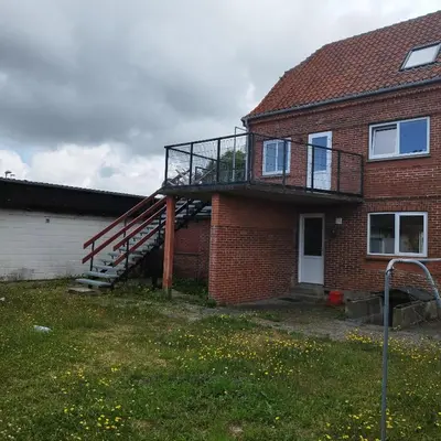 a brick house with a staircase on the side of it at Hyggelig lejlighed i stille by in Vemb