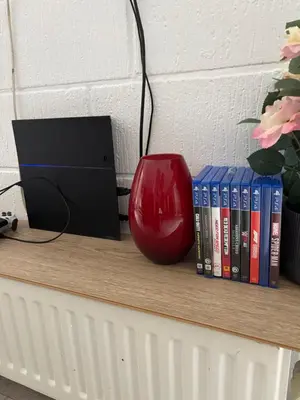 a red vase sitting on a shelf with books at Cozy Newly Renovated Apartment in Nørager