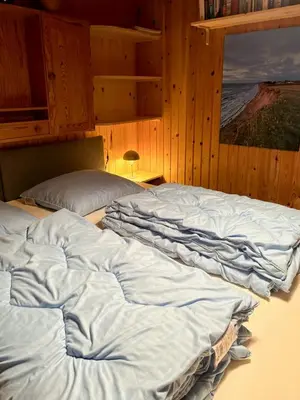 a large unmade bed in a room with a window at Charming Wooden Summer House In Trend in Løgstør