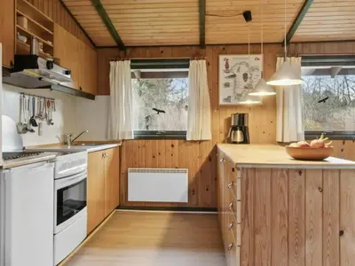 a kitchen with wooden cabinets and white appliances at Charming Wooden Summer House In Trend in Løgstør