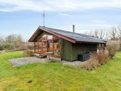 a small green building on a grass field at Charming Wooden Summer House In Trend in Løgstør