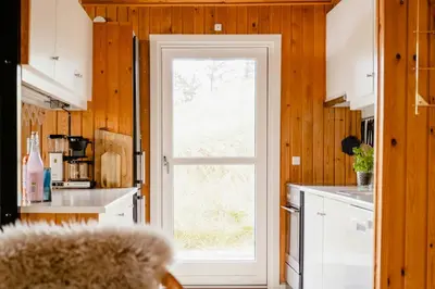 a kitchen with a white door and a window at Nordic 70S Gem Amidst The Dunes in Blokhus