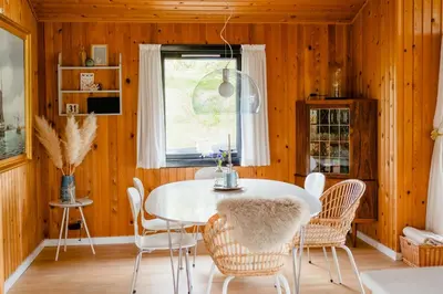 a dining room with a white table and chairs at Nordic 70S Gem Amidst The Dunes in Blokhus