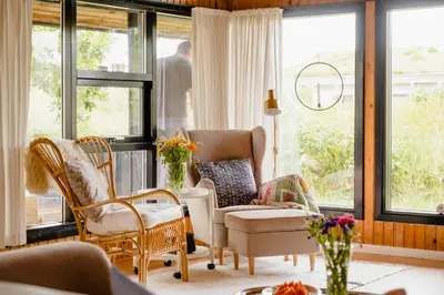 a living room with rocking chairs and windows at Nordic 70S Gem Amidst The Dunes in Blokhus