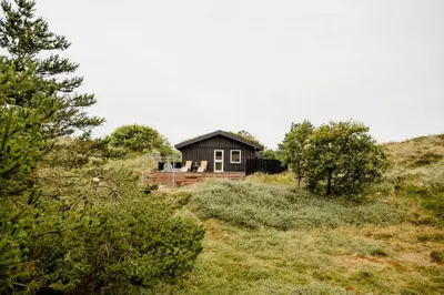 a house on the side of a hill with trees at Nordic 70S Gem Amidst The Dunes in Blokhus